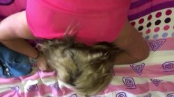 Mujer de pelo rubio y blusa rosa empinada en la cama siendo cogida